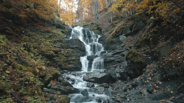 Waterfall Cascade Flows From Large Rocks Among Yellow Trees