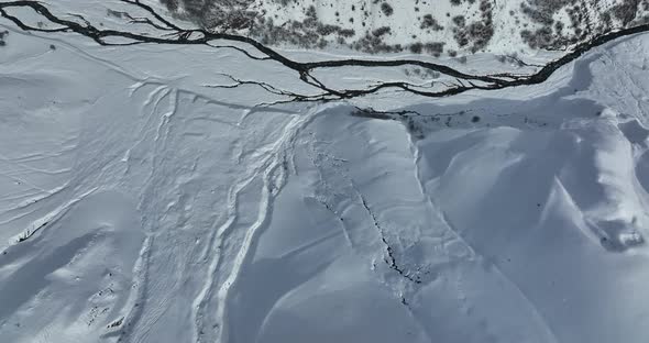 Gudauri, Georgia - January 17 2022: aerial view of the the river flowing in the snowy mountains