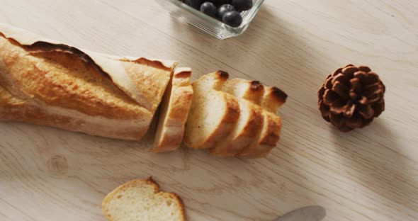 Video of baguette, bluberries and pine cone on a wooden surface