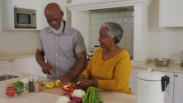 African american senior couple chopping vegetables together in the kitchen at home