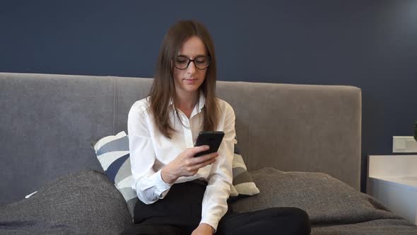 Woman in Glasses Typing on Phone Sitting on Sofa at Home Businesswoman Checks Mail to Study Online