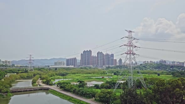 A dynamic aerial shot of high-voltage electric towers along the town of Yuen Long in Hong Kong. Thes