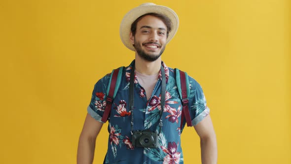 Portrait of Overjoyed Middle Eastern Tourist with Backpack Holding Camera and Smiling