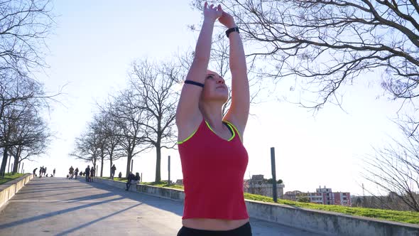 Young sporty woman with leg prosthesis stretching arms in a park