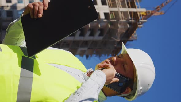 Vertical Foreman Checking Plans and Talking on Phone on Construction Site