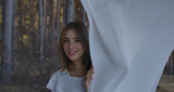 Young Positive Caucasian Woman Peeking Out of White Clothing and Smiling