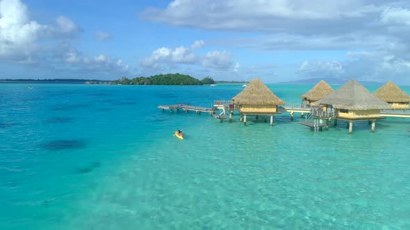 Aerial drone view of a man and woman couple on a tandem sea kayak in Bora Bora tropical island.