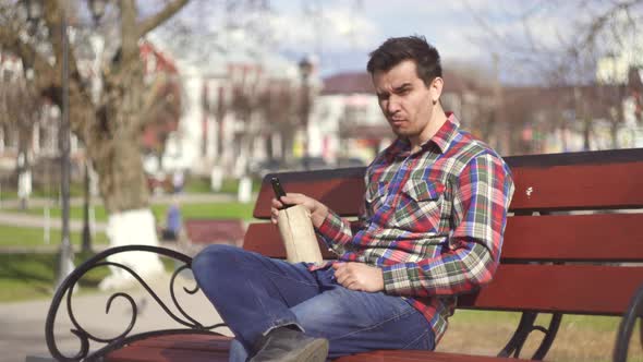 Man in a Shirt Drinking Alcohol in a Park on a Bench