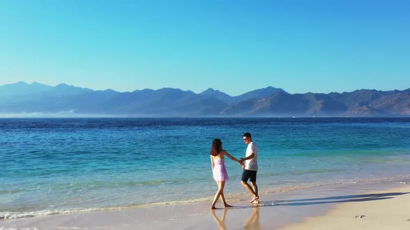 Man and woman tanning on marine bay beach holiday by shallow sea and white sand background of Gili A