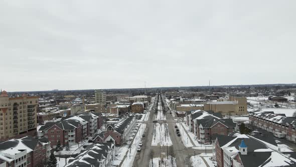 Aerial view down wide street in winter. Multistory buildings on each side of the street.