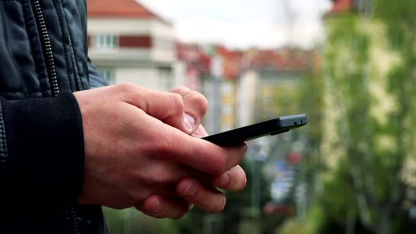 Man Stands and Works on Mobile Phone - Detail of Hands