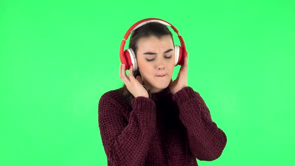 Cheerful Girl Dancing and Enjoys Music in Big Red Headphones. Green Screen