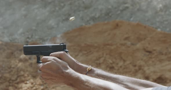 Slow motion of a hand gun firing in a firing range with cartridge flying away