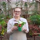 Young Woman Holds Out Pots of Flowers and Smiles - VideoHive Item for Sale
