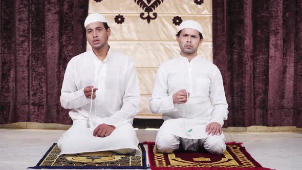 Muslim men worshiping using praying beads