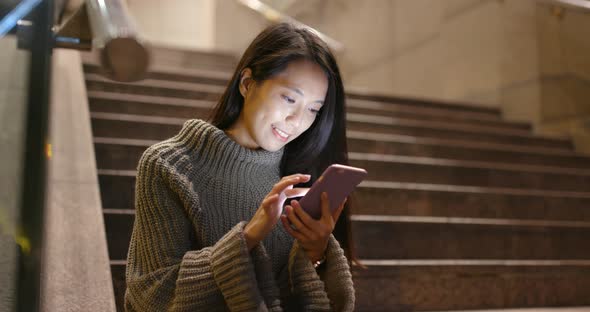 Business woman using mobile phone in the city at night