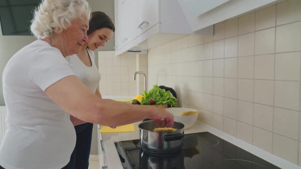 Smiling Woman Helping Grandmother To Cook