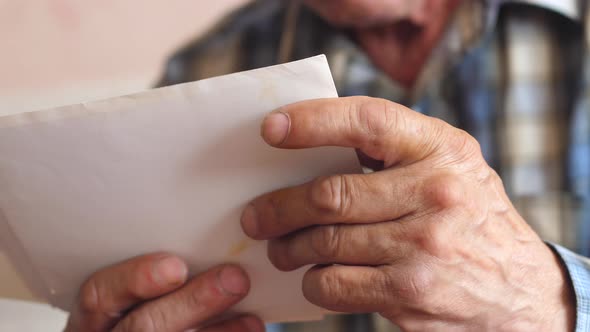  in the wrinkled hands of an elderly man old family photos. a pensioner examines a photo, nostalgia 