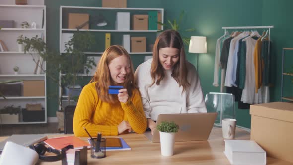 Joyful Girls Students Doing Shopping Together Online with aCredit Card From Home