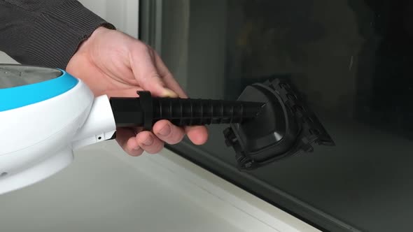 A Man Washes the Joints on Window with a Steam Cleaner