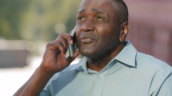 Black Adult Mature African American Man Consultant Sitting Outdoors Holding Smartphone in Hand