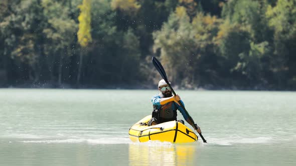 Man is Paddling on Raft Boat in the Mountain Lake