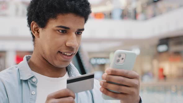 African American Thoughtful Man Client Customer Entering Banking Credit Card Data in Phone Mobile