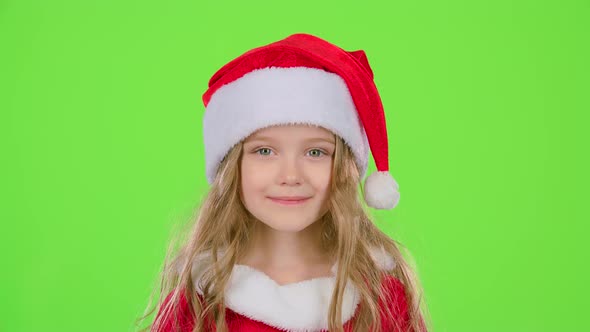 Baby in a Beautiful Suit and a Red New Year's Cap Smiles. Green Screen