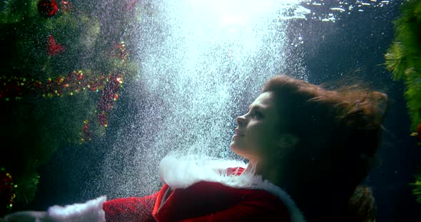 Young Woman Is Immersing Under Water Near Christmas Tree in Pool, New Year