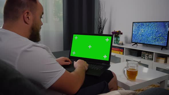 Man sitting on sofa Using Laptop with Greenscreen and Chroma Key