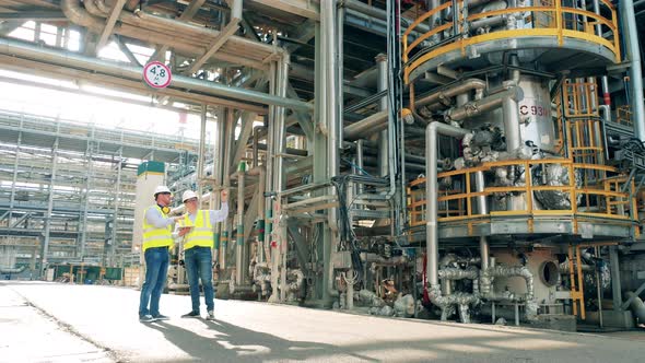 Pipelines of the Petroleum Refinery Being Observed By Two Inspectors