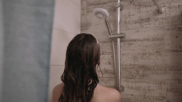 Back Look of Naked Woman Washes Face and Head Under Shower