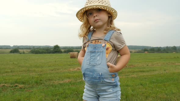 Funny Child Standing on Haystack on Farmer Field. Farmer Daughter Walking in Field