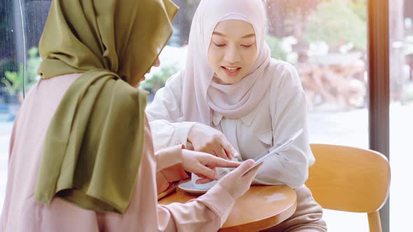 Young beautiful Asian Muslim women enjoying a relaxing moment working and playing with mobile phone