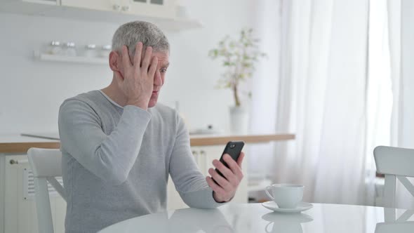 Sad Senior Old Man Having Failure on Smartphone at Home 