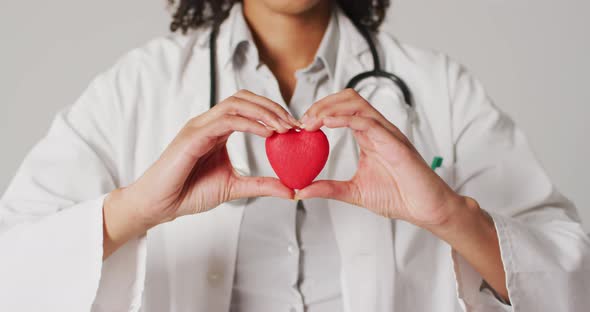 Video of biracial female doctor holding heart on white background