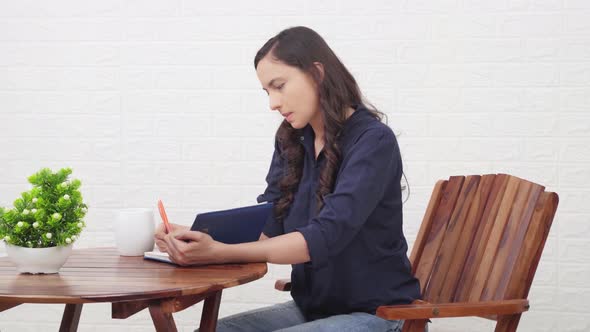 Indian girl writing a book at a cafe