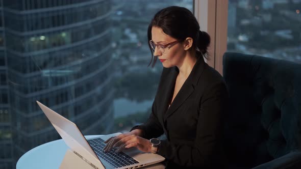 Portrait of Business Woman with Glasses in the Office. Girl Sitting at the Table and Working on a