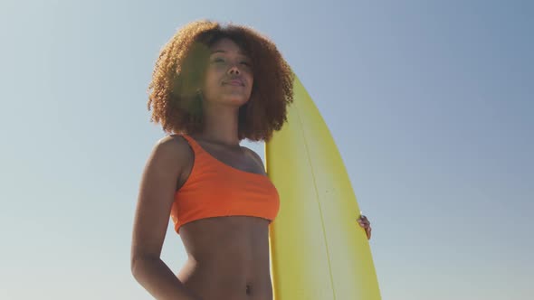African American woman looking at the sea view with surfboard