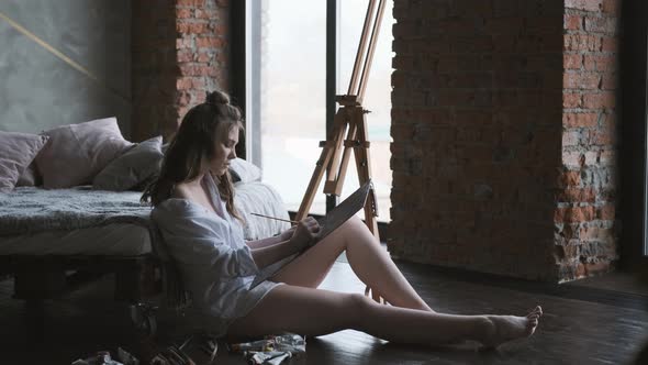 Girl Artist Works Sitting on the Floor in a Home Studio