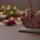 Orbit Shot of Man Writes Christmas Gift List for Holidays in Notepad with a Pencil Under Warm Light - VideoHive Item for Sale