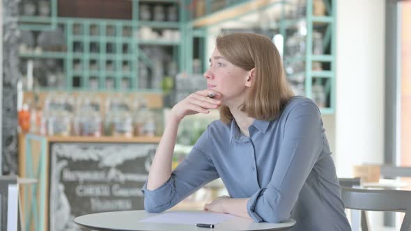 Young Woman Trying to Write on Paper in Cafe