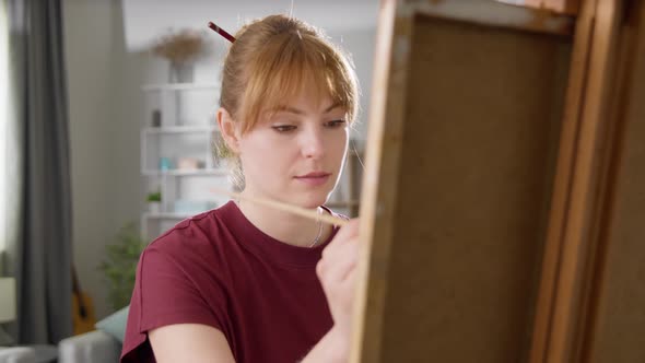 Young Woman Artist Draws a Picture of a House in a Living Room