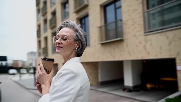 Beautiful Caucasian Elderly Grayhaired Business Woman Drinking Coffee Outdoors