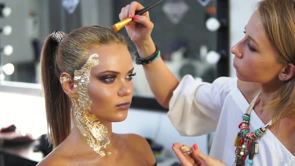 Makeup Artist Applying Golden Shiny Powder on the Model's Hair Using Special Brush