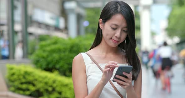 Asian Woman look at the smart phone in city