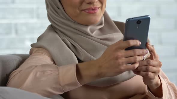 Muslim Female Chatting on Mobile Phone at Home, Testing New App, Technology