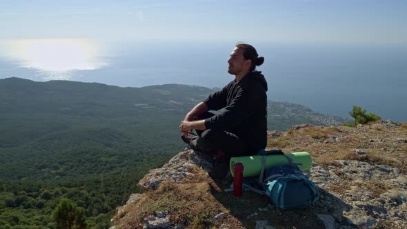 A young tourist is enjoying the sea view from a high mountain.