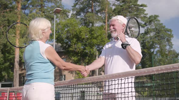 Smiling Mature Couple Shaking Hands After Playing Tennis on the Tennis Court