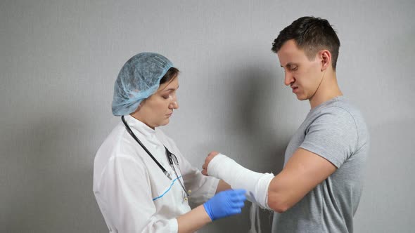 Brunette Doctor Examines Broken Forearm of Young Man